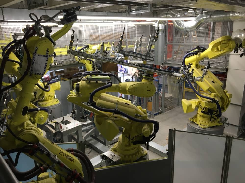 Skupina žlutých robotických ramen FANUC při práci v buňce.